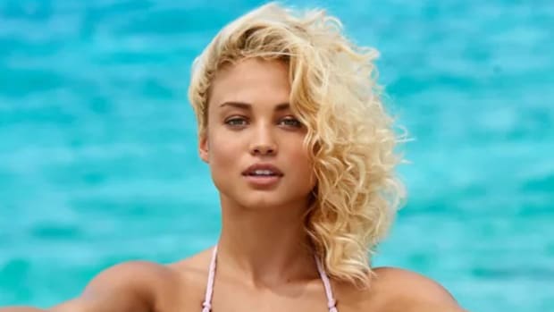 Rose Bertram poses in a bikini in front of the bright blue water.